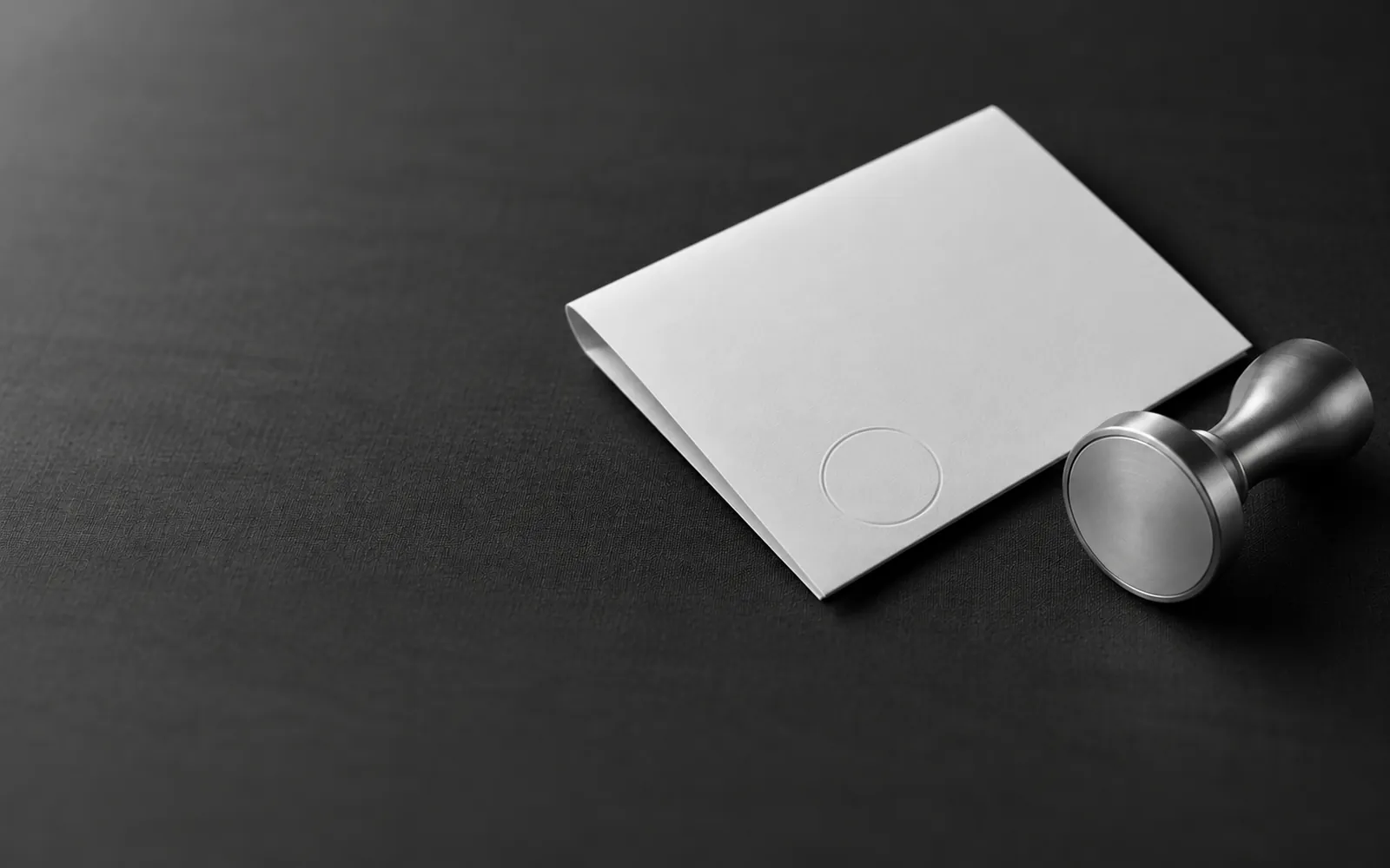 A steel stamp beside a folded white sheet, the moment before approval.